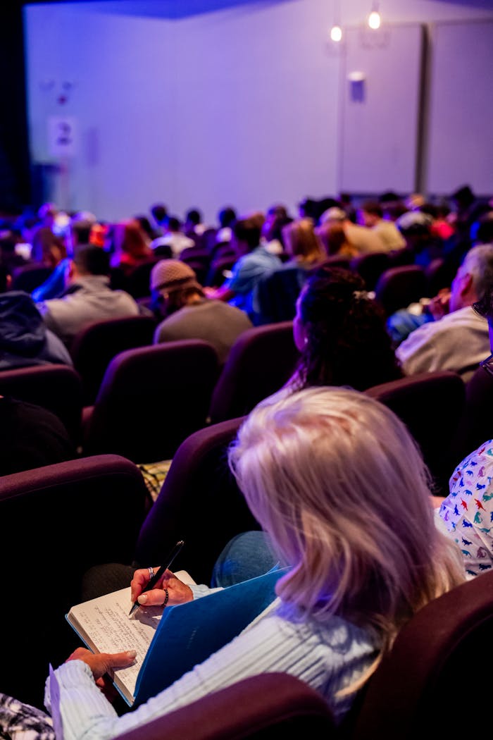 The Art of Drawing Readers In: Your attractive post title goes here A diverse group of adults attending a conference, taking notes in an auditorium.